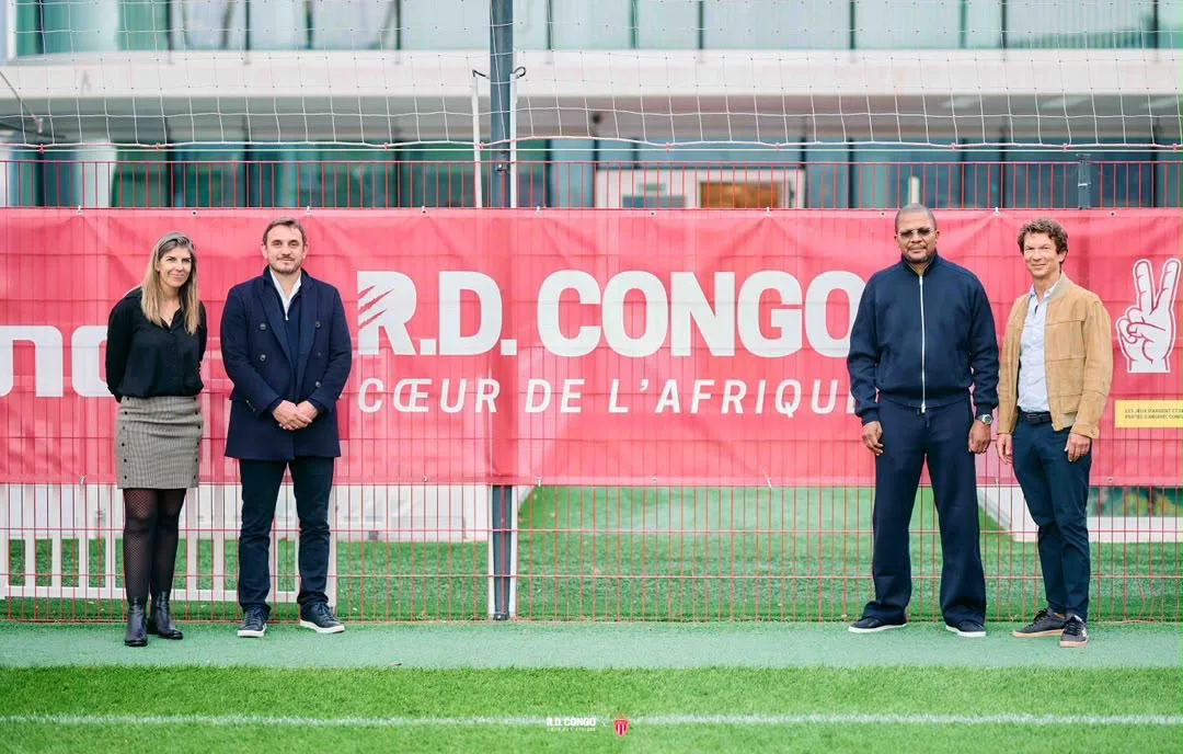 Minister Didier Budimbu in front of the R.D. Congo — Heart of Africa banner at AS Monaco’s performance centre